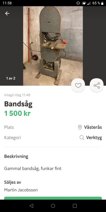 Gammal vertikal bandsåg i ett garage, placerad bredvid en röd verktygsstång.