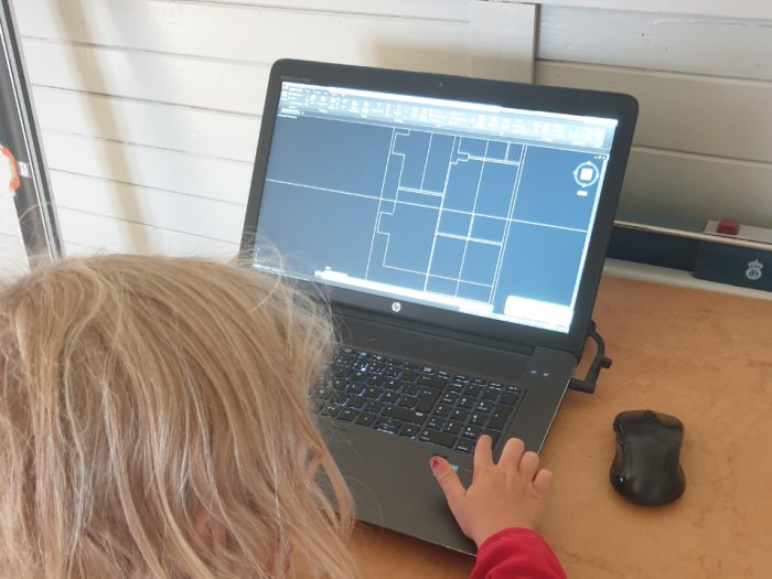 Barn använder CAD-program på laptop för att rita husplaner.