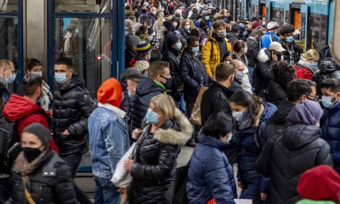 Folk i ansiktsmasker på en trång plattform i Frankfurt under pandemi.