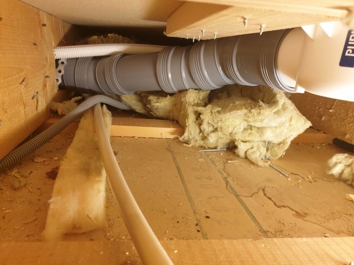 Fuktigt golv med lösa plattor, sprucket tätskikt och dåligt monterad golvbrunn under renovering.