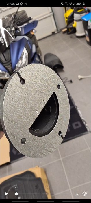 Närbild på basen av en lyktstolpe med fästhål, inomhusmiljö med motorcykel i bakgrunden.
