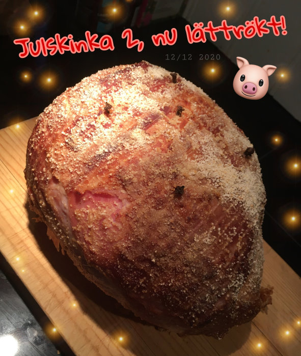 En saftig julskinka på en skärbräda med texten "Julskinka 2, nu lätttrökt!" och dekorativa emoji-ikoner.