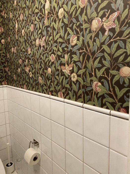 Nymonterad tapet med retro 50-talsmönster ovanför vit kakelvägg i ett badrum.