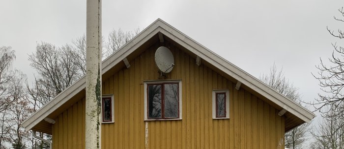 Gavel på hus med nytt tak under uppbyggnad, gult trämaterial på väggarna och vita fönsterkarmar.