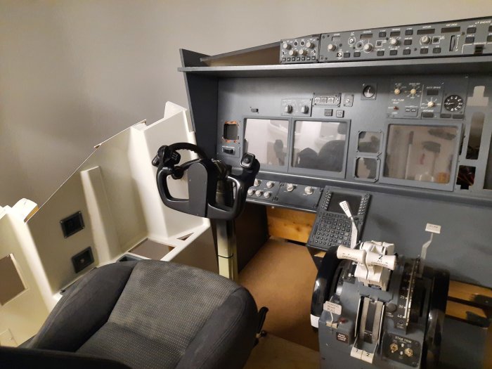 Replika av Boeing 737ng cockpit med styrspak, instrumentpaneler och sits i ett förråd.