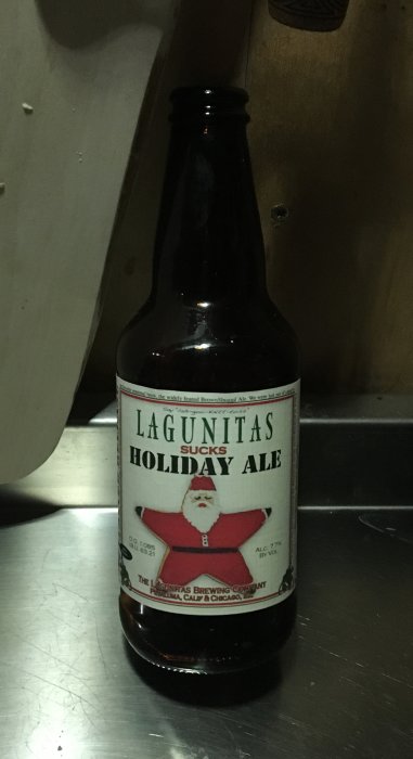 Flaska med Lagunitas Holiday Ale på ett mörkt underlag, festligt etikett med tomte.