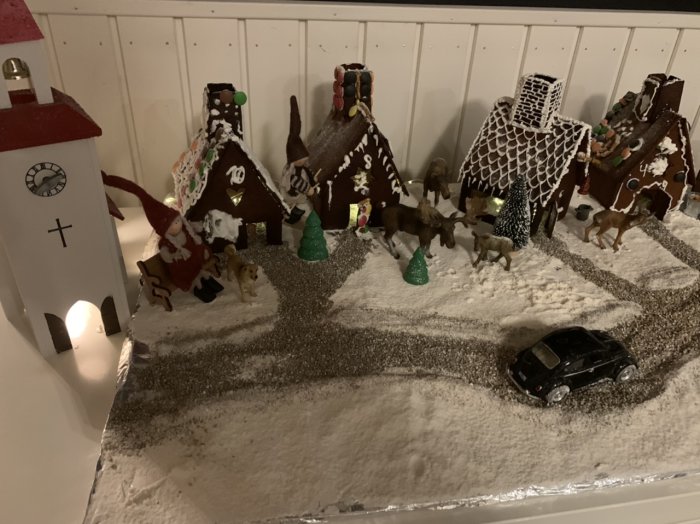 Handgjorda pepparkakshus representerar en familjs bidrag till tävlingen med dekorerade tak och väggar, små djurfigurer och mjöl som snö.