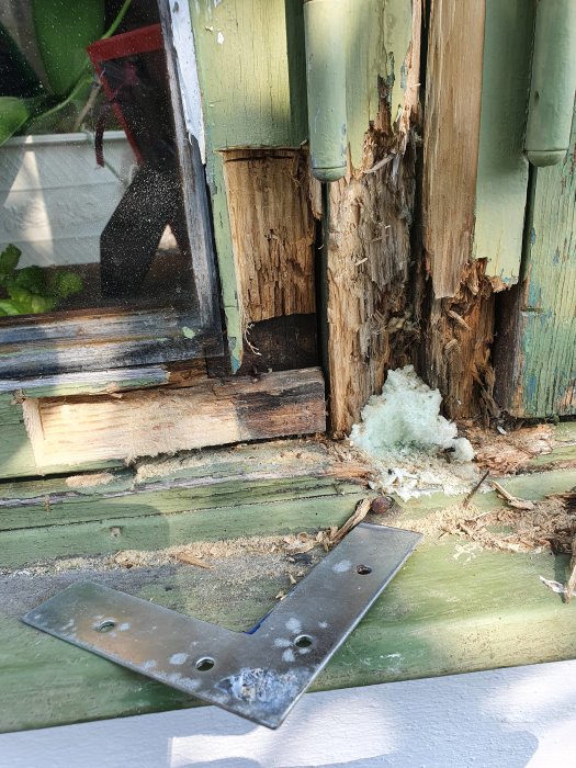 Rotskadad fönsterkarm med synliga skador på trä och förstärkningsvinkel.