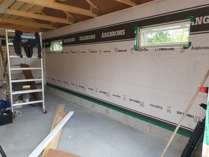 Garage med isolerade väggar, tätskikt och tätade fönster, stege och byggmaterial syns.