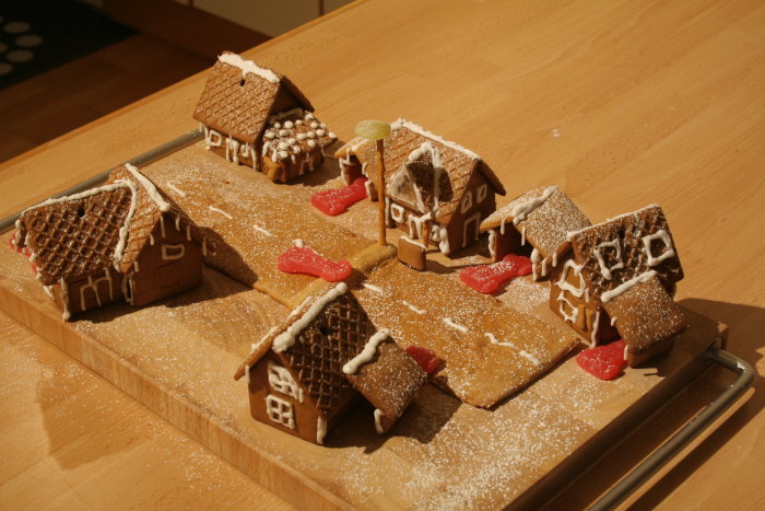 Pepparkakshus som formar en gata med ett hus nära en lyktstolpe, simulerar en byggprojektmodell.