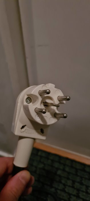 Hand som håller en perilexplugg avsedd för koppling av spishäll med 3-fas och nolla.