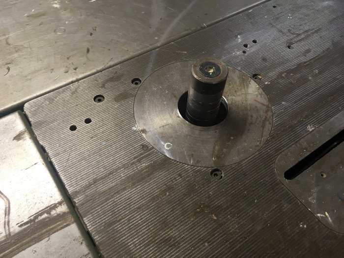 Välanvänd överhandsfräs monterad i arbetsbord med fräshållare och inställningsmöjligheter.