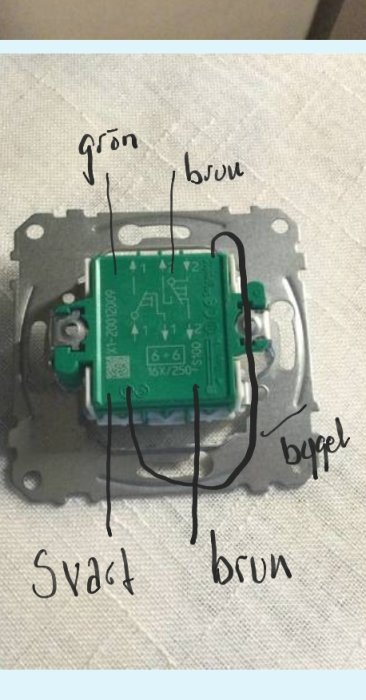 Elektrisk kopplingsdosa med anvisningar handskrivna för att byta trådarna grön och brun till positioner märkta med "1" och "2".