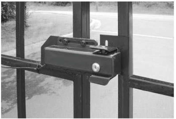 Elektroniskt dörrlås installerat på glasdörr med utsikt mot en svängd väg.