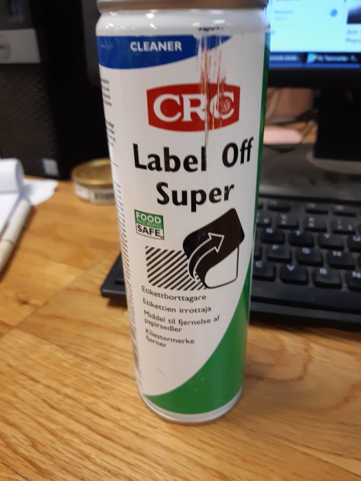 Burk av CRC Label Off Super rengöringsmedel på ett bord framför en datorskärm.