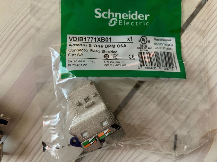 RJ45 Cat 6A nätverksuttag och förpackning från Schneider Electric på ett bord.