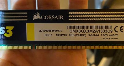 Hand håller ett Corsair DDR3 8GB RAM-minne framför en suddig bakgrund.
