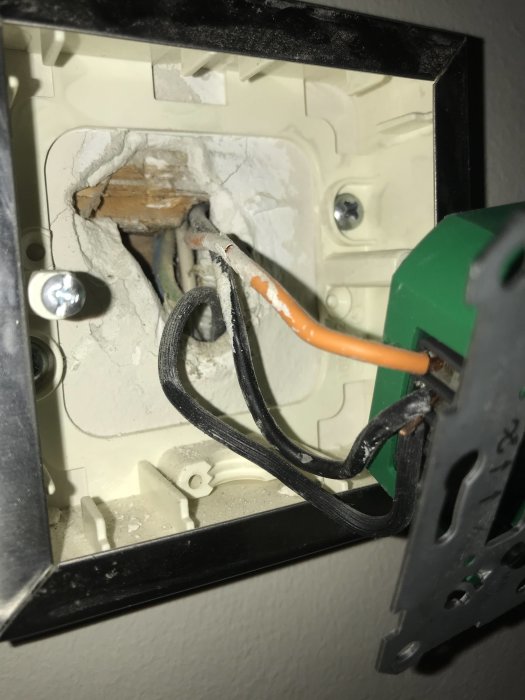 Eluttag med öppen kabeldragning som visar en blå, en vit och en jordtråd, samt en orange och två svarta kablar.