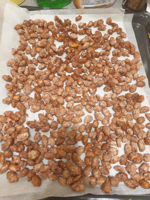 Nyrostade nötter med kanelströssel på bakplåtspapper.