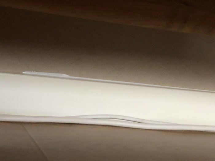 Ojämnt övermålad golvlist med spackel och färgkladdar.