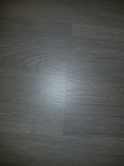 Grått laminatgolv med synlig skarv mellan plankorna.