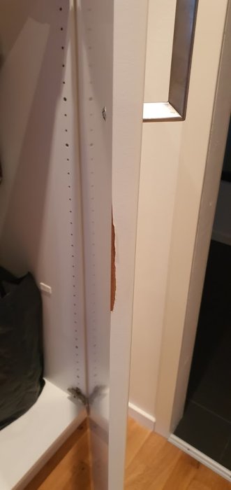 Skadad färg på luckkanten av vit skåpslucka bredvid ugn, tecken på luftläckage.