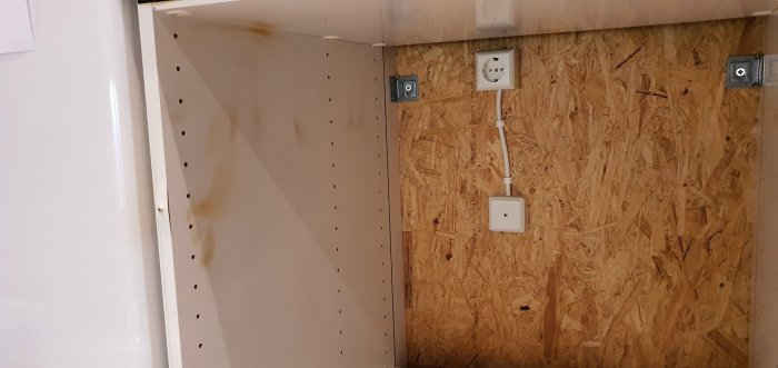 Köksskåp med färgskador orsakade av luftläckage från ugn, synliga skruvar och eluttag.