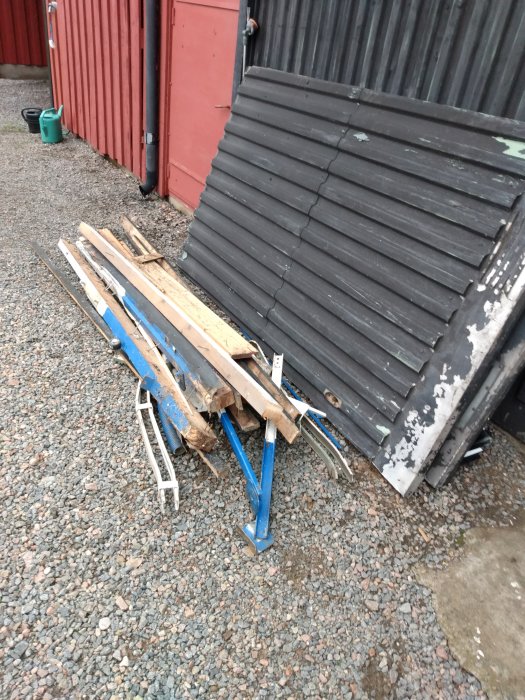 Nymålat garagefoder vid gammal garageport och material staplat på marken, väntar på panelbyte.