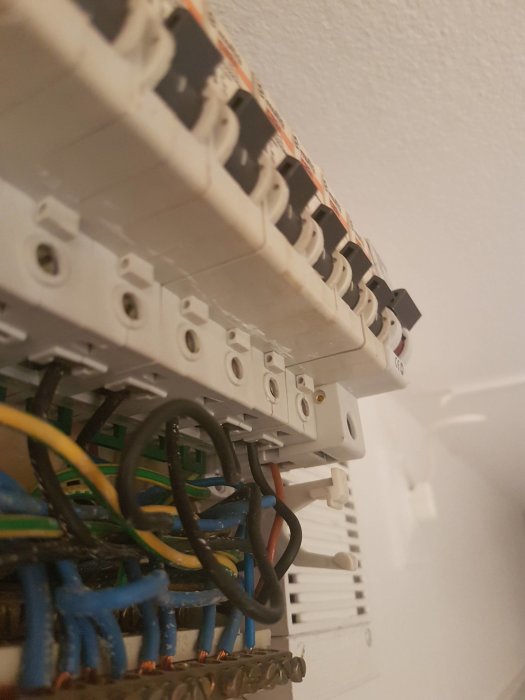 Närbild på en öppen elcentral med synliga ledningar och ny dvärgbrytare som sticker ut.