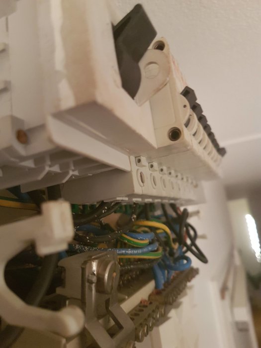 Öppen elcentral med synliga kablar och terminaler, märkt med "220V" på en bricka, indikerar äldre installation.