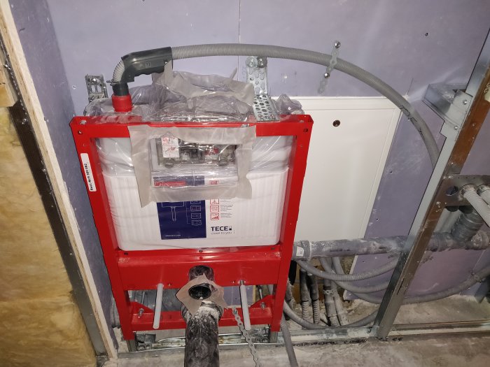 Installation av WC-fixtur med VVS-arbeten synliga, inklusive rör och avstånd som inte följer standarden CC 40.