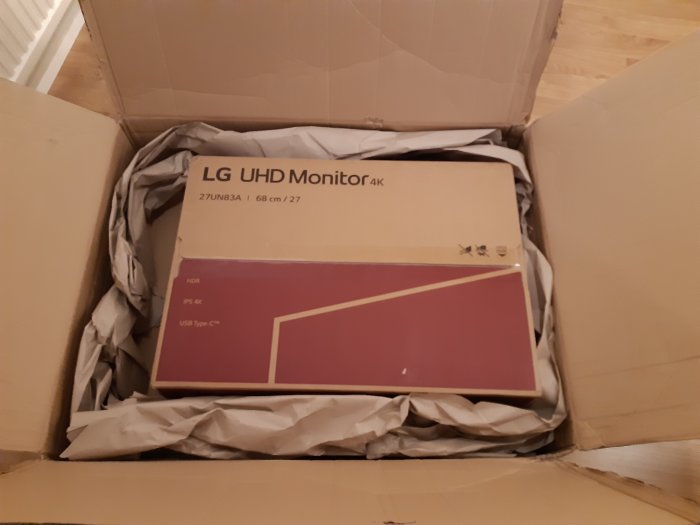 LG UHD 4K monitorlåda i en öppen kartong med packmaterial, förväxlad med en beställd bordssåg.