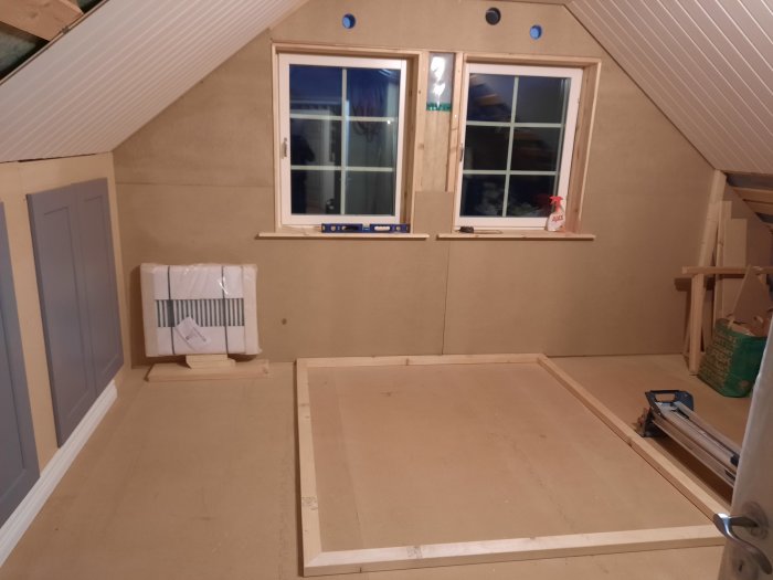 Ovanvåning under inredning med provisorisk sängram och radiator ej under fönster.