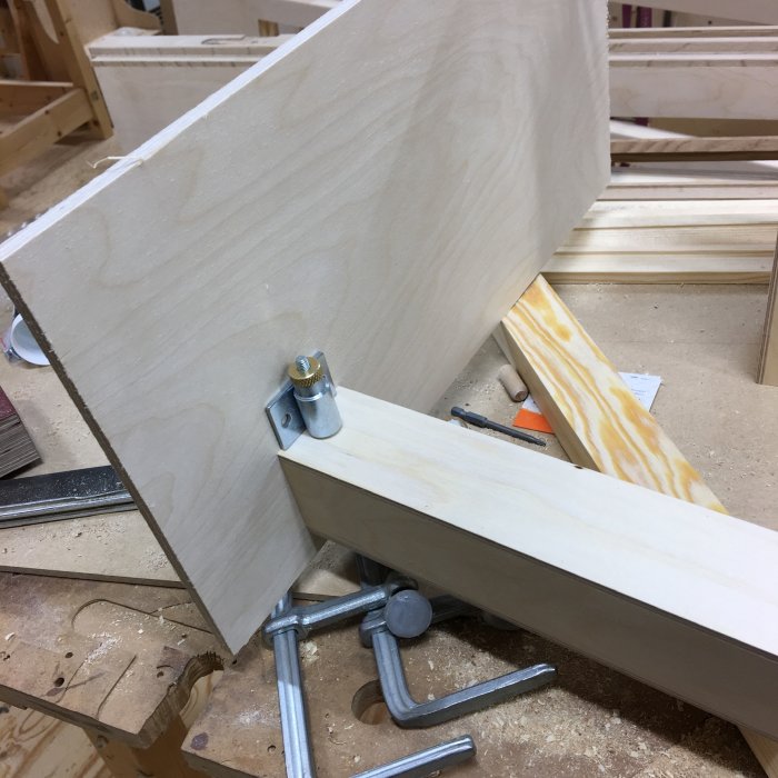 Trädelar och verktyg i verkstad med plywoodbit och boxlås i byggprocessen.