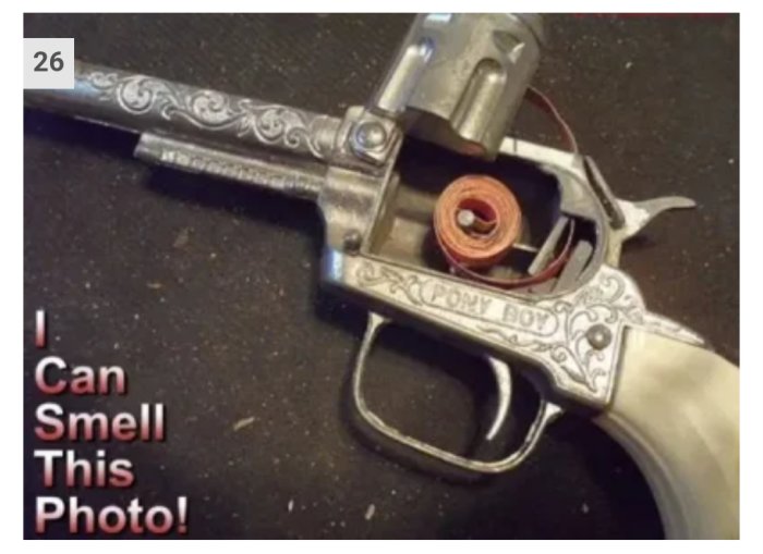 Närbild av en öppen leksakspistol med märkningen "PONY BOY", kapselremsa och texten "I Can Smell This Photo!
