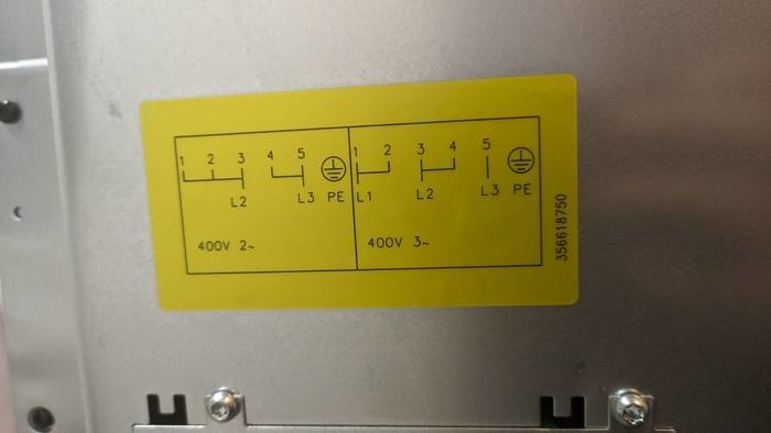 Etikett med kopplingsschema för 400V 2- och 3-fas elektrisk anslutning på en metallpanel.