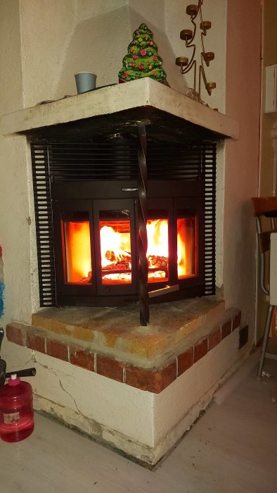 Nymonterad Jötul c400 Harmony braskamin med öppen spjäll och brinnande ved inuti, väntar på golvplatta.