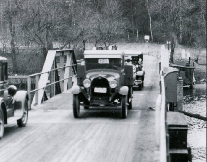 Svartvit bild från 1929 som visar gammal motorfordon på svängbron.