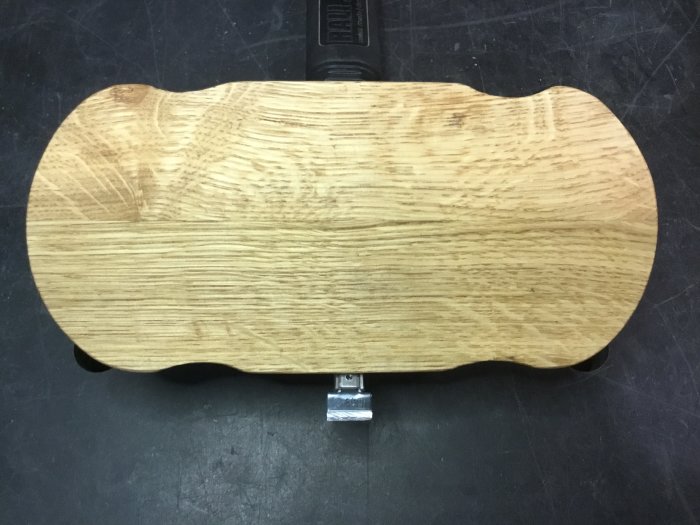 Handgjord massiv ekrouter plane med kurvig design och monterat stämjärn, placerad på en arbetsyta.