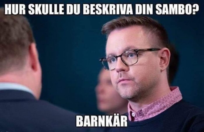 Man i glasögon och rosa skjorta med texten "Hur skulle du beskriva din sambo? Barnkär