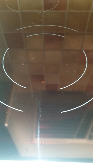 Glaskeramikhäll med små fläckar eller prickar inuti, synliga mot bakgrundsbelysning.