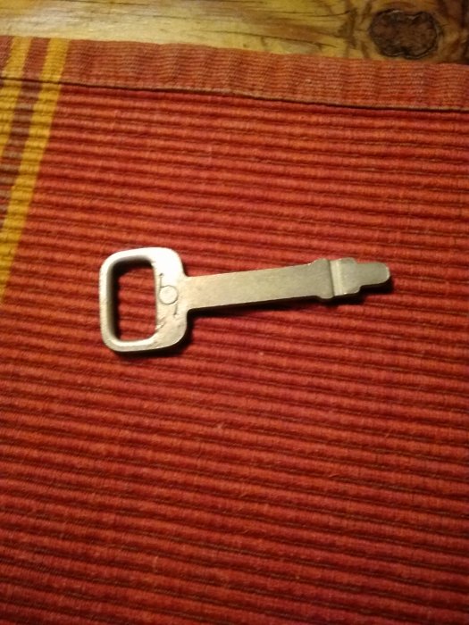 En enkel metallnyckel på ett rödrandigt tygunderlag.