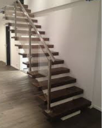 Modernt utformad flytande trappa med trästeg och metallräcken i en inomhusmiljö.