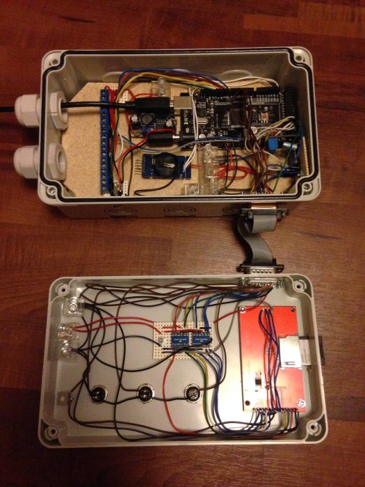 Öppen elektroniklåda med kretskort, kablar och komponenter synligt arrangerade på de inre panelerna.