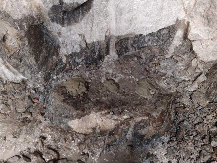 Berggrund med horisontella hål fyllda med finbetong, använda för att plugga hålen vid användning av snigeldynamit.