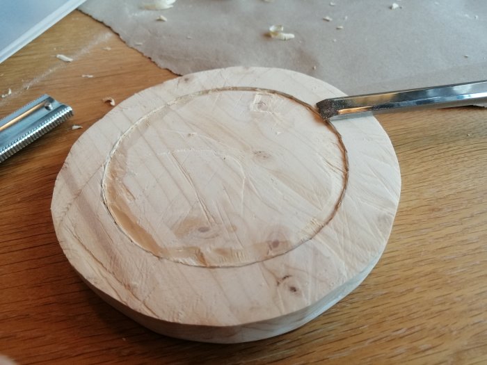 Trädel med urfasad cirkel för huvud på byggprojekt, närbild på arbetsbord med snickarverktyg.