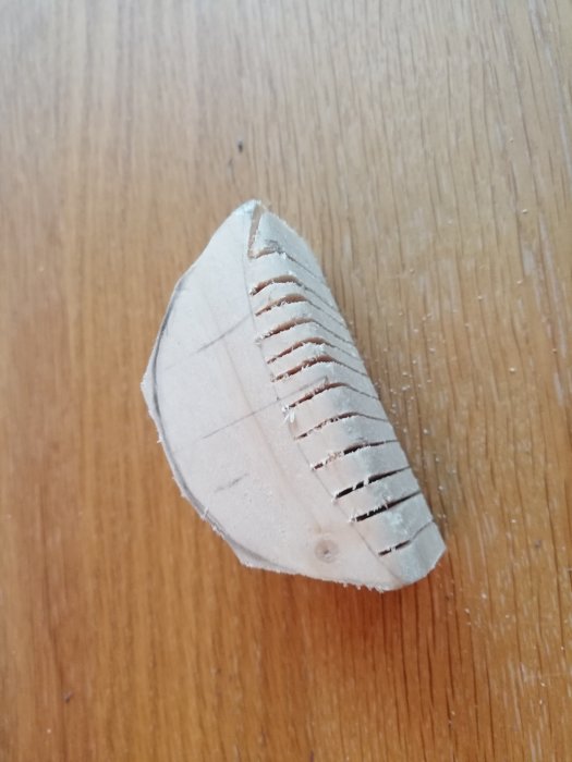 Träsvarvad del med urfasad undersida och sågade spår för vingmontering.