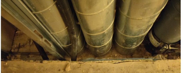 Glipa mellan golv och vägg bakom avloppsrör i byggprojekt, cirka 1-1.5 cm bred.