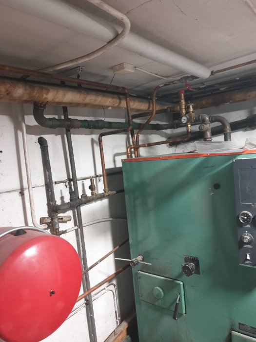 Oljepanna i ett pannrum med synliga rörkopplingar, expansionskärl och en mätare som visar 2.5 bar.