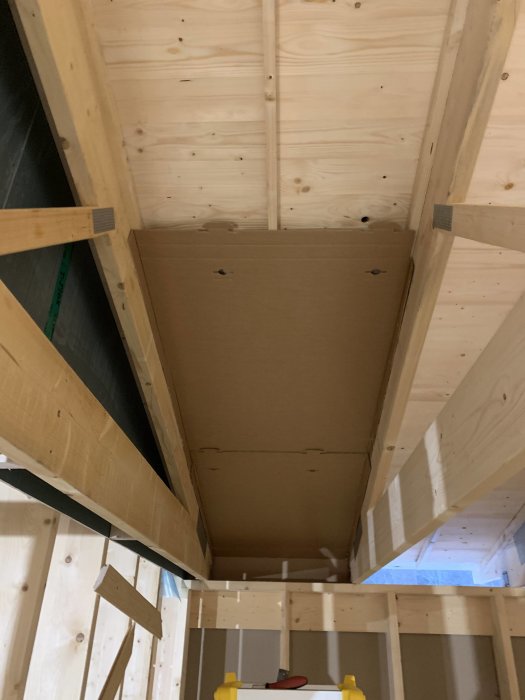 Påbörjad installation av luftspalt i ett garage med synliga träbalkar och en del täckt med masonit.